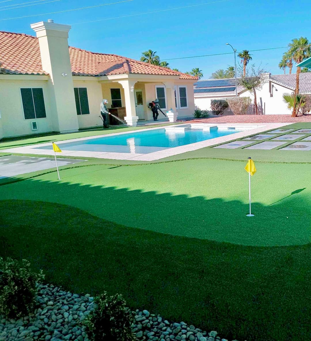 Modern home with a swimming pool and a golf putting green in the backyard. Sunny day scene.